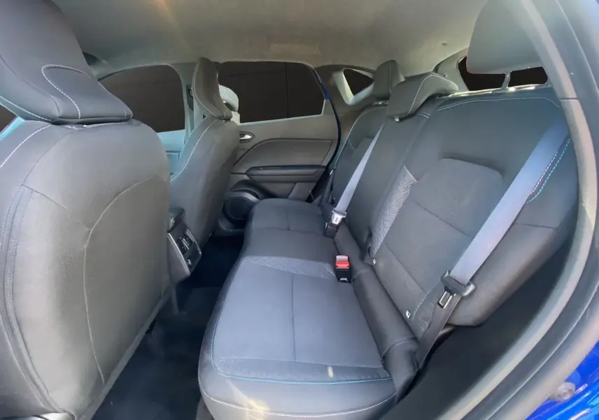 Vue intérieure arrière du Renault Captur 2024 bleu Iron, montrant les sièges arrière en tissu noir avec surpiqûres bleues.