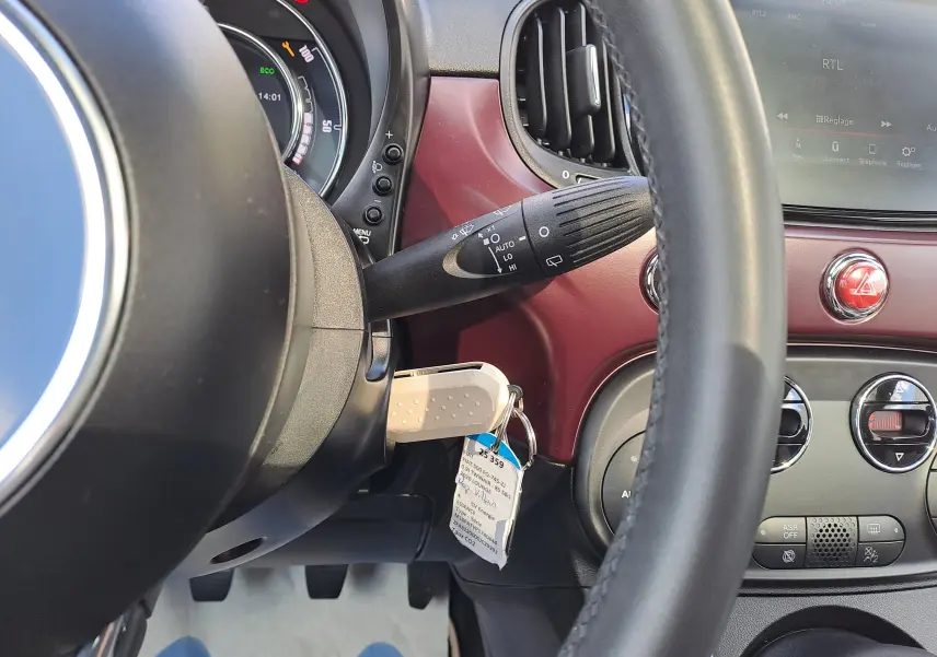 Vue rapprochée du tableau de bord bordeaux d'une Fiat 500 2020, avec volant et commandes visibles.