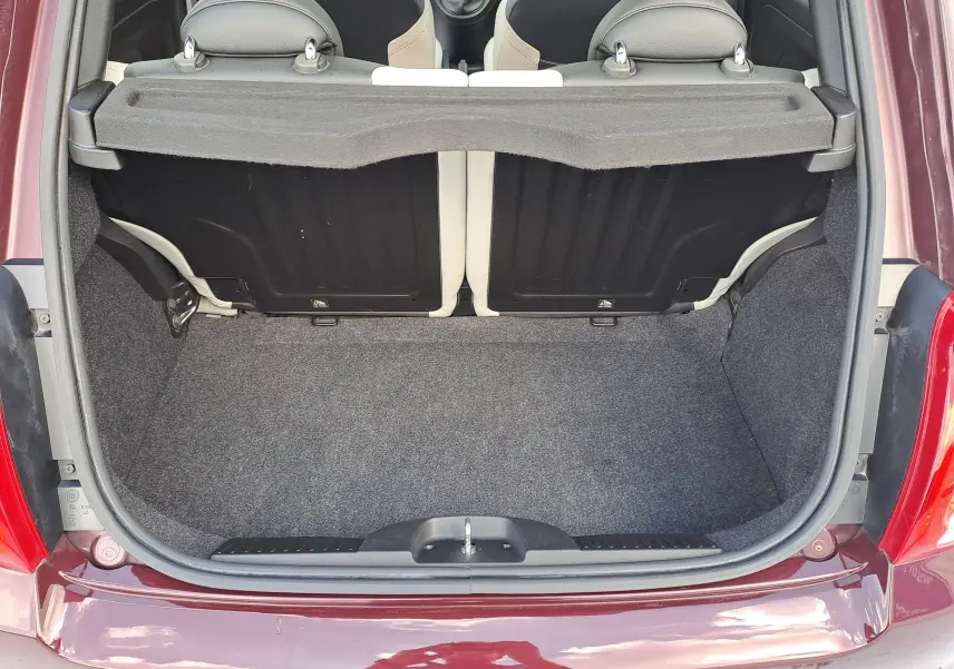 Coffre ouvert vu de l'arrière d'une FIAT 500 Opera Bordeaux Metal, montrant l'espace de chargement et les dossiers de sièges noirs.