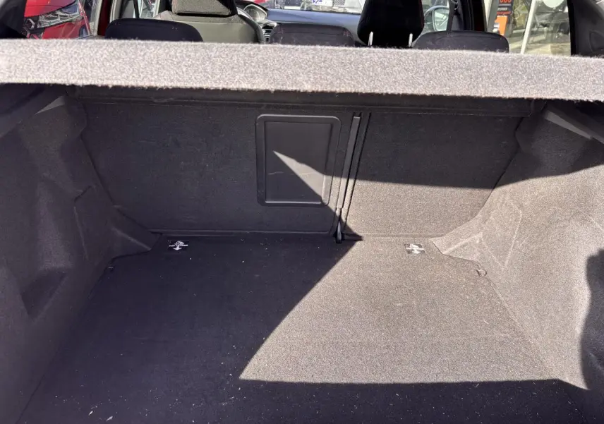 Coffre ouvert de la Peugeot 308 rouge foncé, montrant l'espace de chargement intérieur avec banquette arrière en arrière-plan.