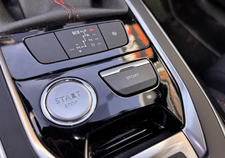 Gros plan sur la console centrale noire brillante de la Peugeot 308 GT Line avec bouton Start/Stop et touche Sport.
