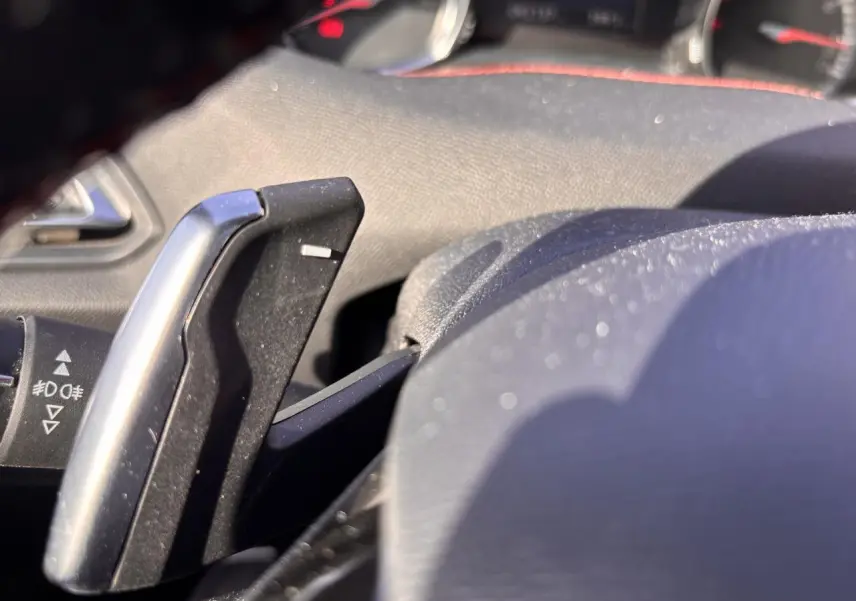 Gros plan sur la palette de changement de vitesse en aluminium à droite du volant d'une Peugeot 308 GT Line rouge foncé.