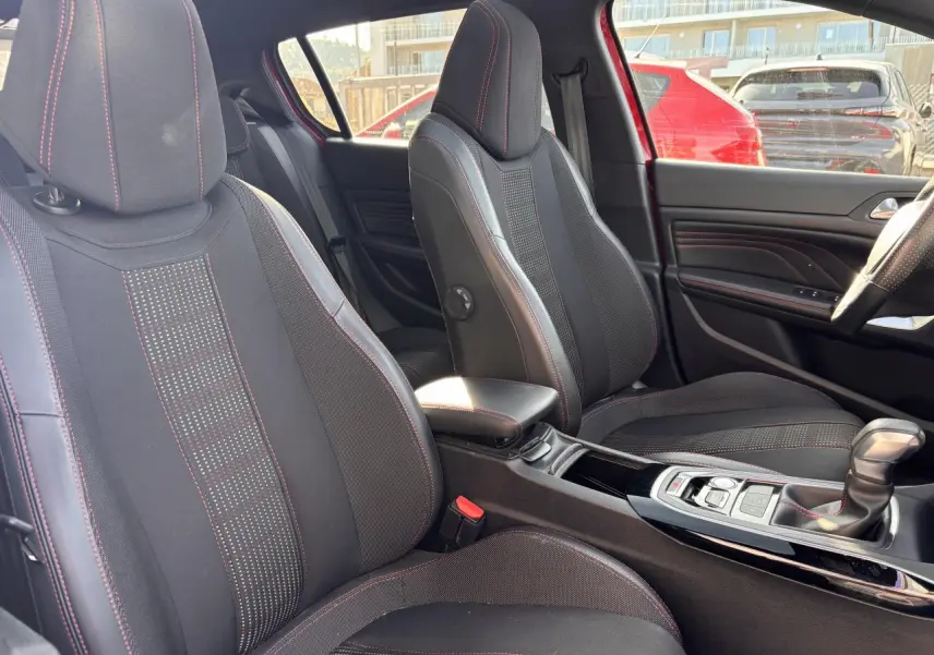 Intérieur de la Peugeot 308 GT Line 2016, vue côté droit sur sièges sport noirs avec surpiqûres rouges et console centrale.