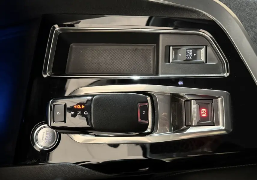 Vue rapprochée de la console centrale noire brillante du Peugeot 5008 avec levier de vitesse automatique et bouton start/stop.