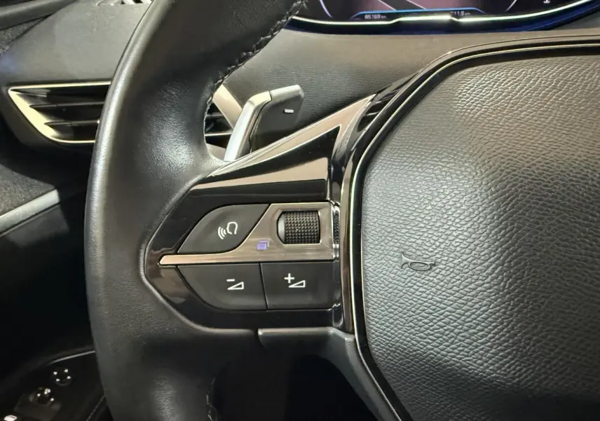 Gros plan sur le volant cuir noir du Peugeot 5008 2021, avec commandes multifonctions et palettes au volant.