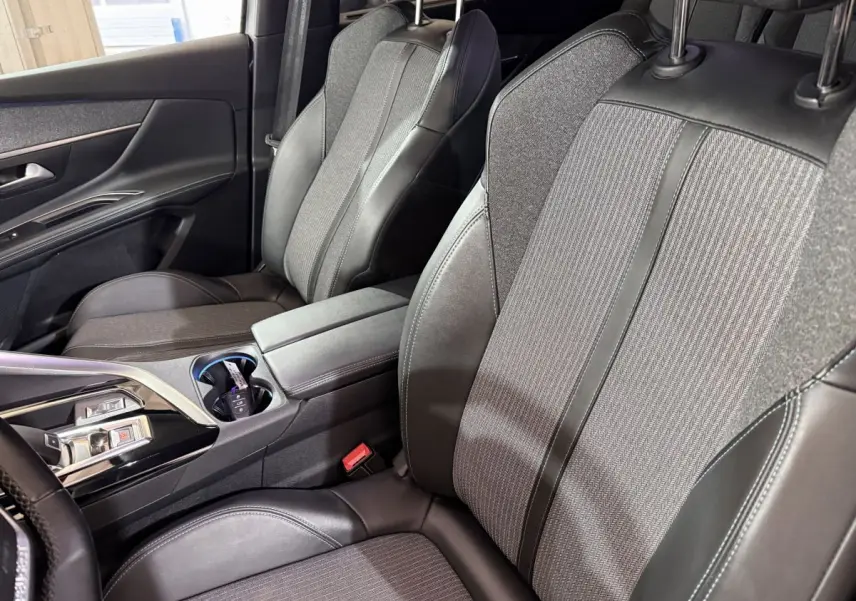 Vue intérieure côté droit des sièges avant gris tissu et cuir du Peugeot 5008 2021 avec console centrale et accoudoir.