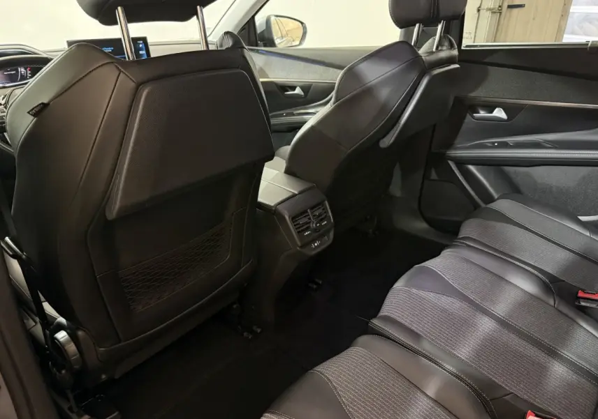 Vue intérieure arrière droite du Peugeot 5008 2021, sièges en cuir noir et console centrale avec aérateurs.