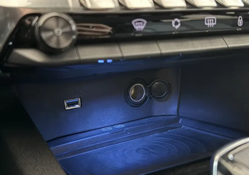 Gros plan sur la prise USB et l’allume-cigare dans l’espace de rangement avant du Peugeot 5008 gris clair 2021.