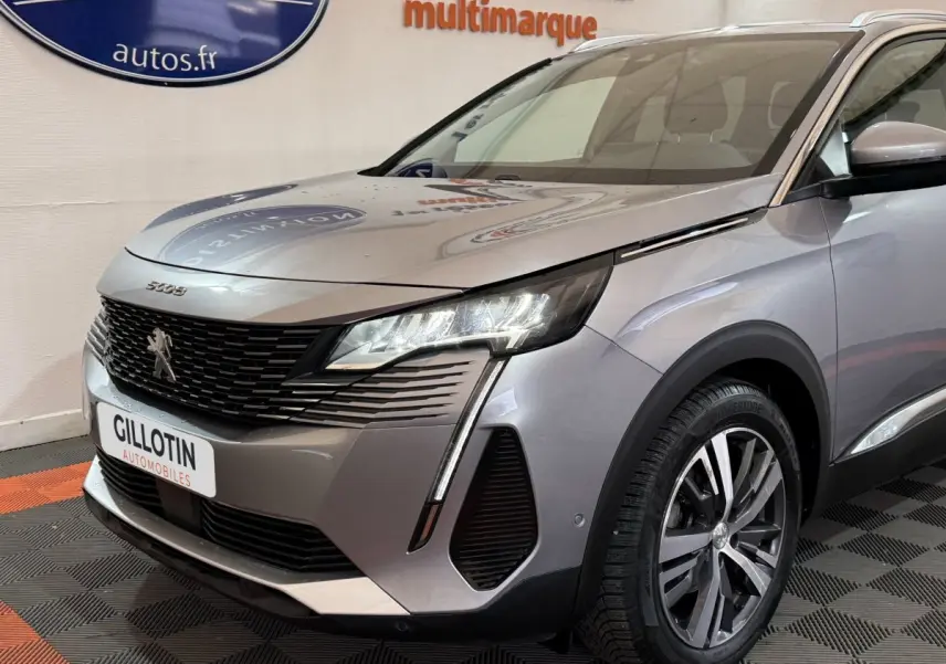 Vue 3/4 avant droit du Peugeot 5008 gris clair 2021 avec phares LED et calandre noire distinctive.