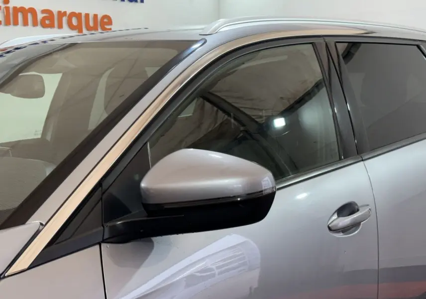 Vue rapprochée du côté gauche d’un Peugeot 5008 gris clair, mettant en valeur le rétroviseur électrique et la poignée de porte.