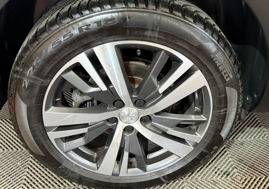 Gros plan sur la jante alliage gris et noir avec logo Peugeot, montée sur pneu Pirelli 225/55 R18.