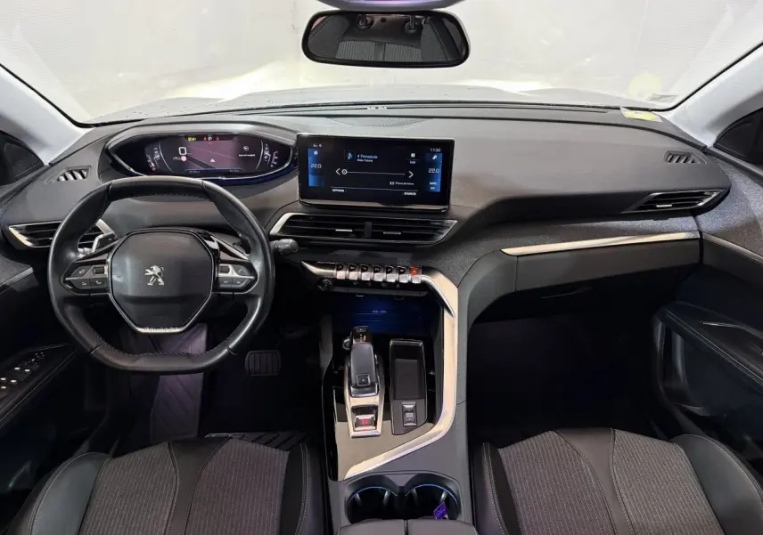Vue intérieure avant du Peugeot 5008 gris clair 2021, tableau de bord moderne avec écran tactile et volant cuir multifonctions.