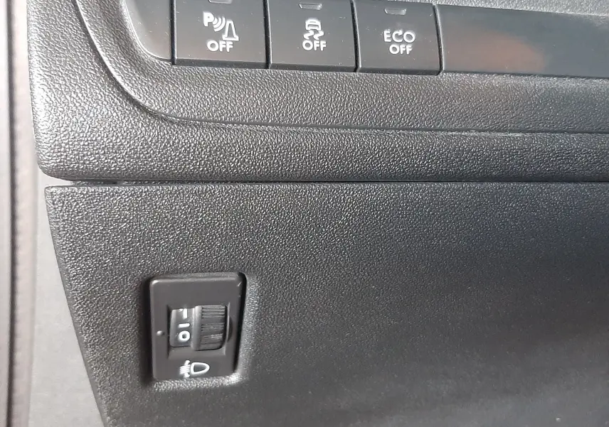 Gros plan sur les commandes de réglages et désactivation des aides à la conduite dans l'habitacle noir du Peugeot 2008 rouge 2016.