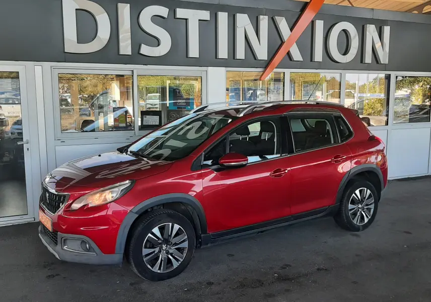 Peugeot 2008 rouge vue de profil côté gauche, garée devant une concession avec enseigne Distinxion.
