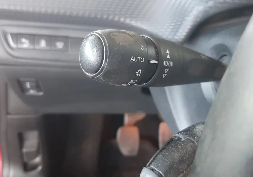 Gros plan sur la commande des feux et régulateur de vitesse dans l'habitacle noir d'une Peugeot 2008 rouge de 2016