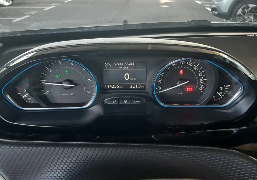 Vue rapprochée du tableau de bord digital d'une Peugeot 2008 rouge, affichant 114255 km et vitesse à 0 km/h.