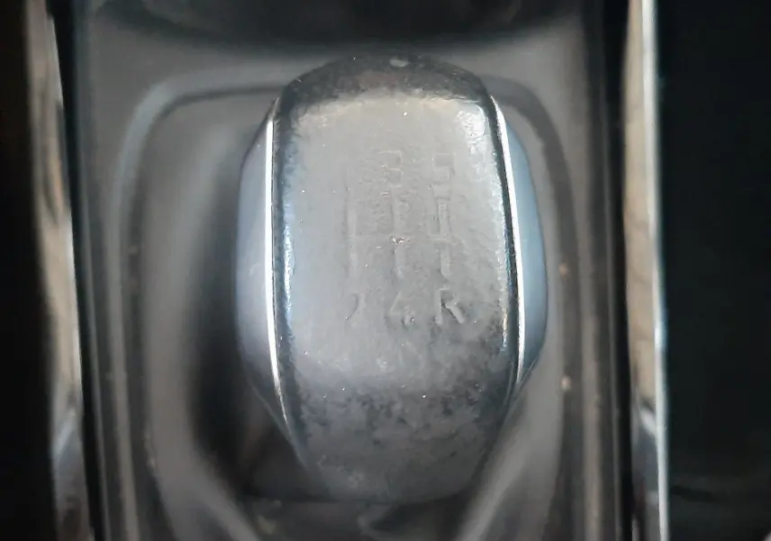 Gros plan sur le levier de vitesses manuel noir de la Peugeot 2008 rouge, montrant les positions des rapports.