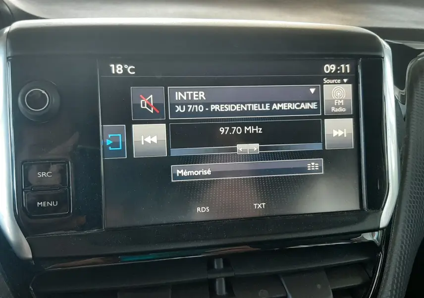 Écran central tactile du tableau de bord de la Peugeot 2008 rouge de 2016 affichant une radio FM à 97,7 MHz.