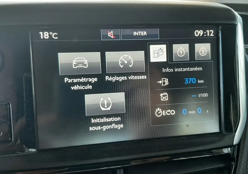 Écran tactile central du tableau de bord du Peugeot 2008 rouge de 2016 affichant les réglages du véhicule et l'autonomie restante.