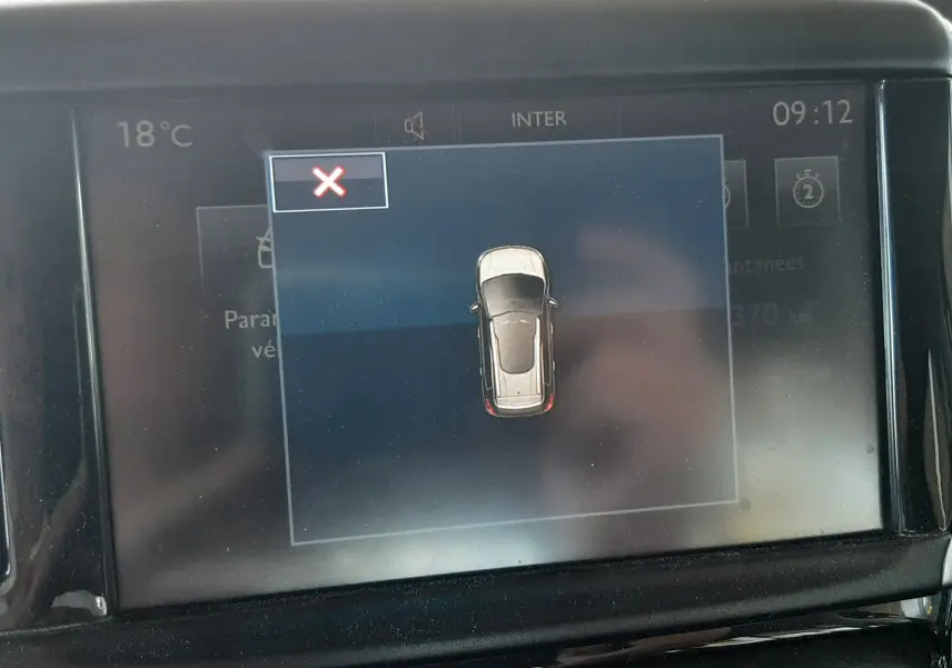 Affichage central du tableau de bord montrant une vue aérienne stylisée du véhicule Peugeot 2008 rouge en mode stationnement.