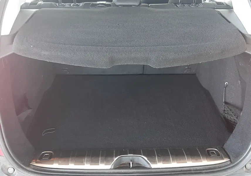 Coffre ouvert d'un Peugeot 2008 rouge, vue arrière montrant l'espace de chargement et l'intérieur noir du véhicule.