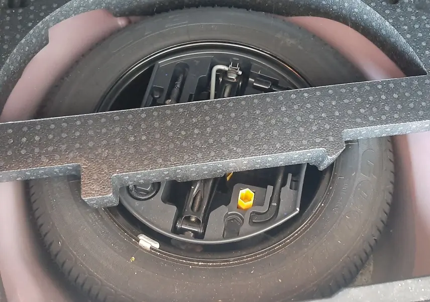 Roue de secours et outils de bord dans le coffre d'une Peugeot 2008 rouge 2016, version essence 1.2 PureTech.