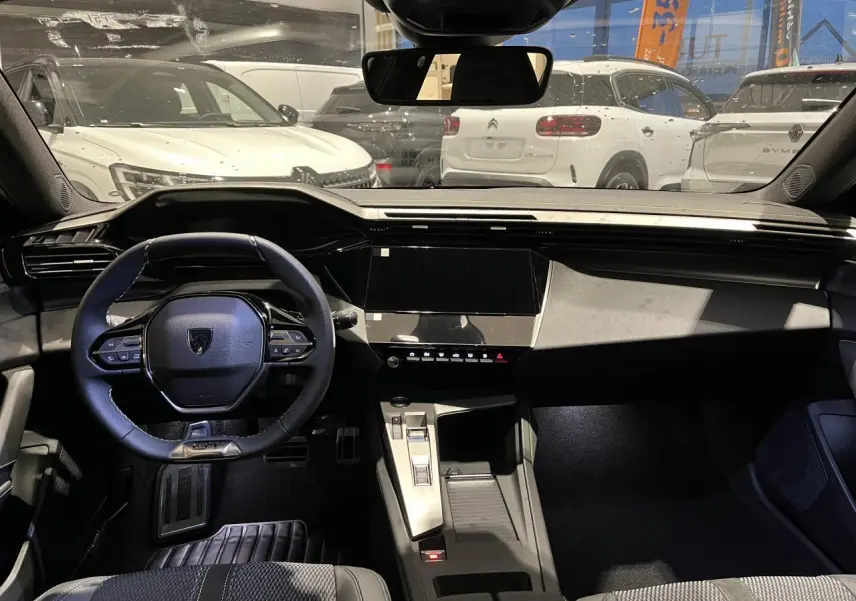 Vue intérieure avant du Peugeot 308 gris selenium 2024, volant cuir et tableau de bord numérique moderne.