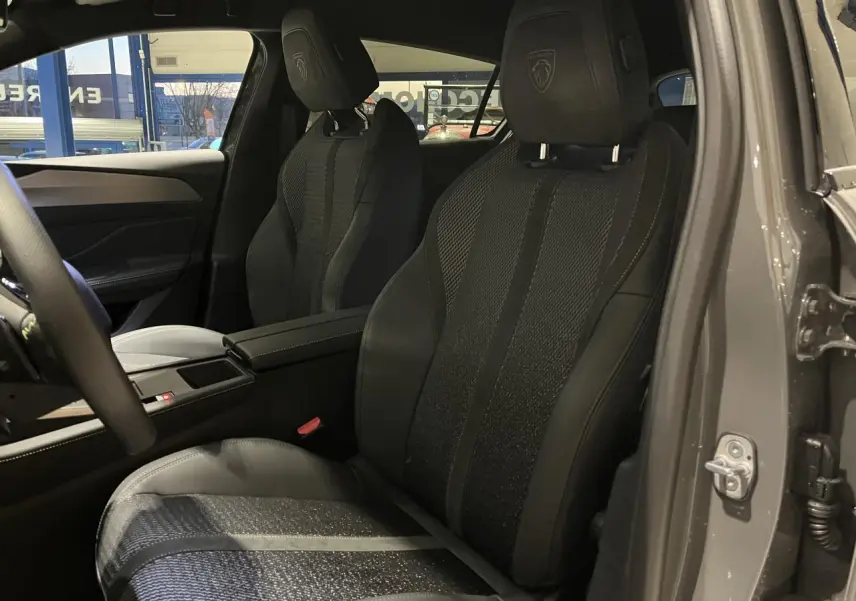 Sièges avant noirs en tissu et cuir avec logo Peugeot, vue intérieure côté gauche d'une 308 GT gris selenium 2024.