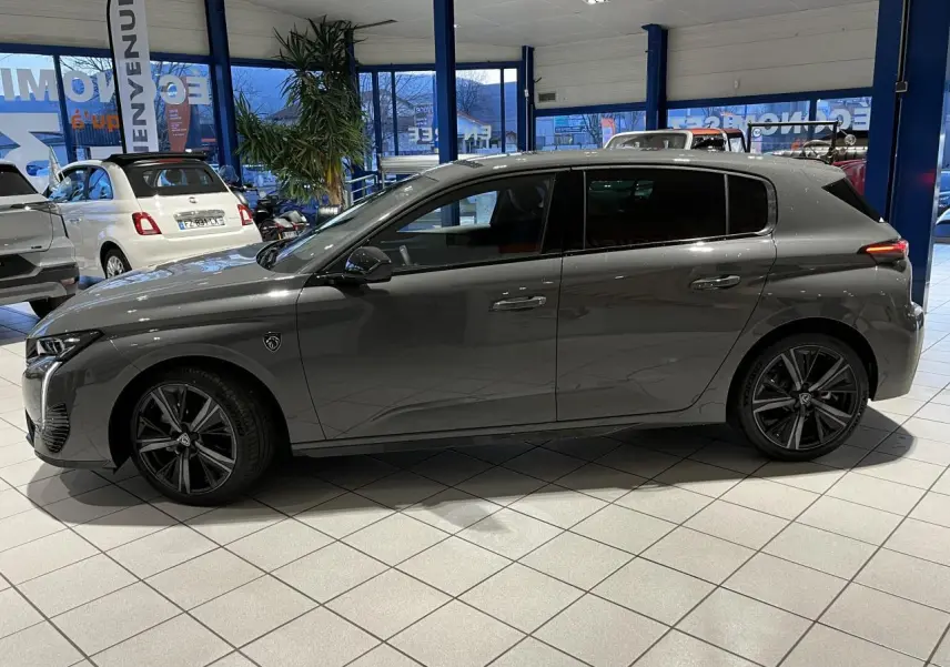 Profil côté gauche de la Peugeot 308 GT gris sélénium avec jantes alliage 18'' Kamakura en showroom.