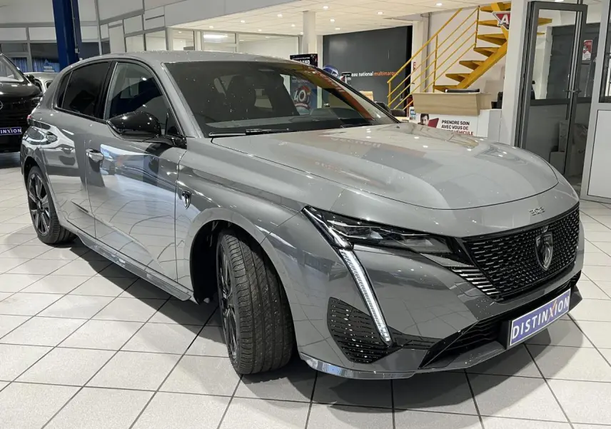 PEUGEOT 308 gris selenium en 3/4 avant droit, avec calandre noire brillante et feux LED griffés.