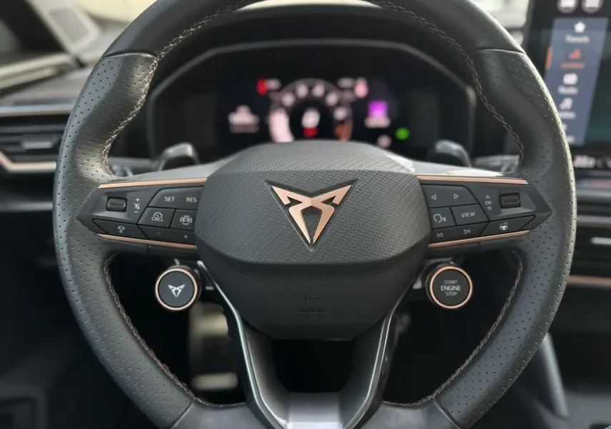 Volant cuir perforé avec logo CUPRA cuivré et commandes intégrées, intérieur moderne du Formentor 2025.