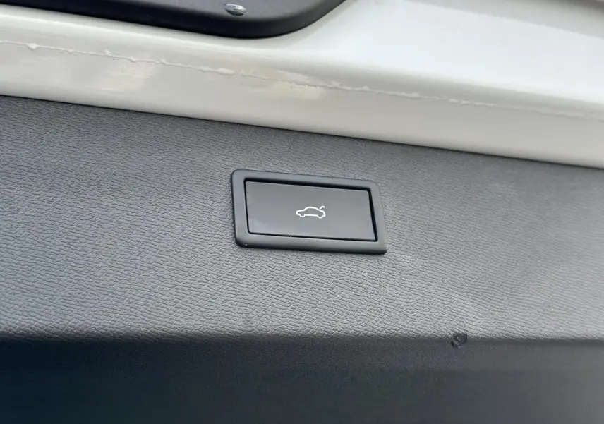 Gros plan sur le bouton d'ouverture électrique du hayon, intégré dans le coffre blanc neige du CUPRA Formentor 2025.