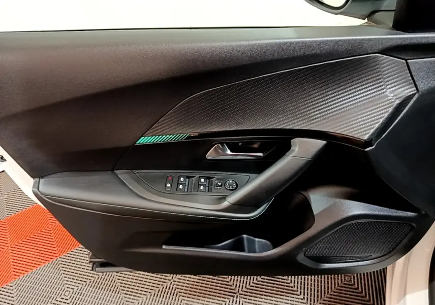 Détail de la porte avant gauche du Peugeot 2008 blanc, avec insert décoratif noir et commandes électriques des vitres.
