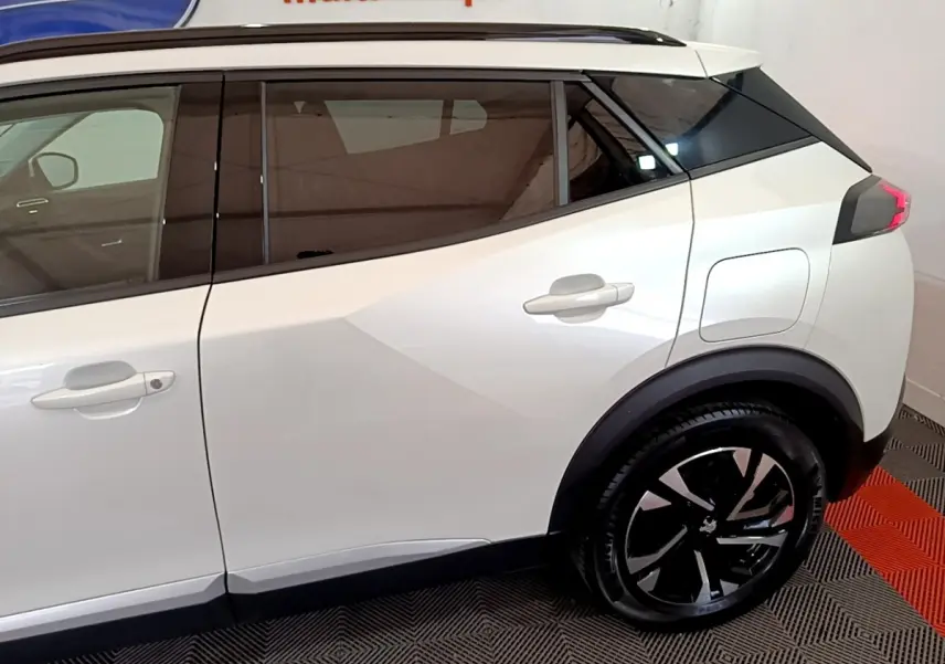 Profil droit du Peugeot 2008 blanc avec vitres teintées et jantes noires au design moderne.