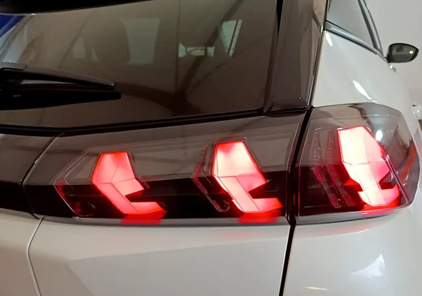 Gros plan sur le feu arrière droit rouge allumé d’un Peugeot 2008 blanc, vue arrière côté droit.