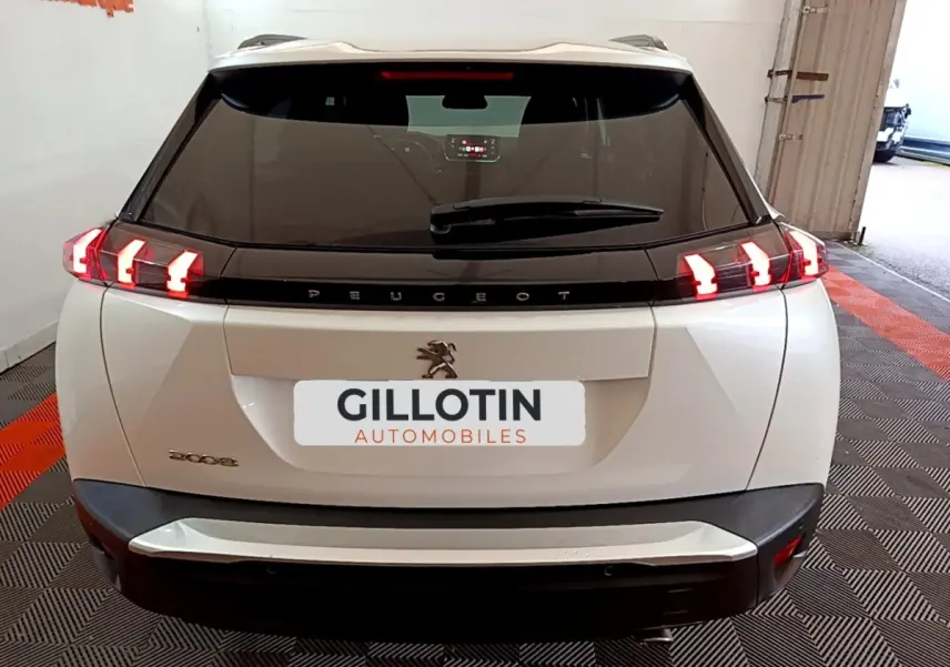 Vue arrière d'un Peugeot 2008 blanc avec feux LED caractéristiques allumés dans un garage.