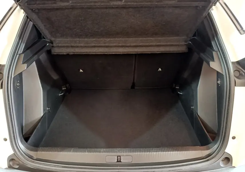 Coffre ouvert vu de face d’un Peugeot 2008 blanc, montrant l’espace de chargement vide et la tablette arrière relevée.