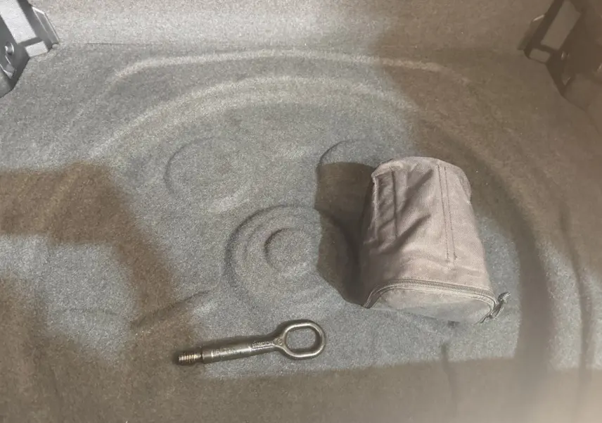 Vue intérieure du coffre gris clair du Volkswagen Tiguan 2020, avec outil d'arrimage et pochette de rangement.