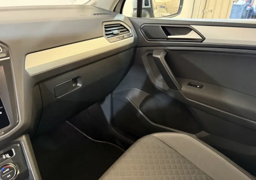 Vue intérieure côté passager du Volkswagen Tiguan 2020 gris clair, avec tableau de bord et garniture beige clair.