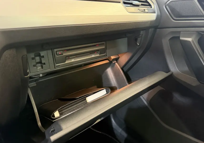 Vue rapprochée de la boîte à gants ouverte côté passager du Volkswagen Tiguan 2020 gris clair, avec manuel de bord visible.