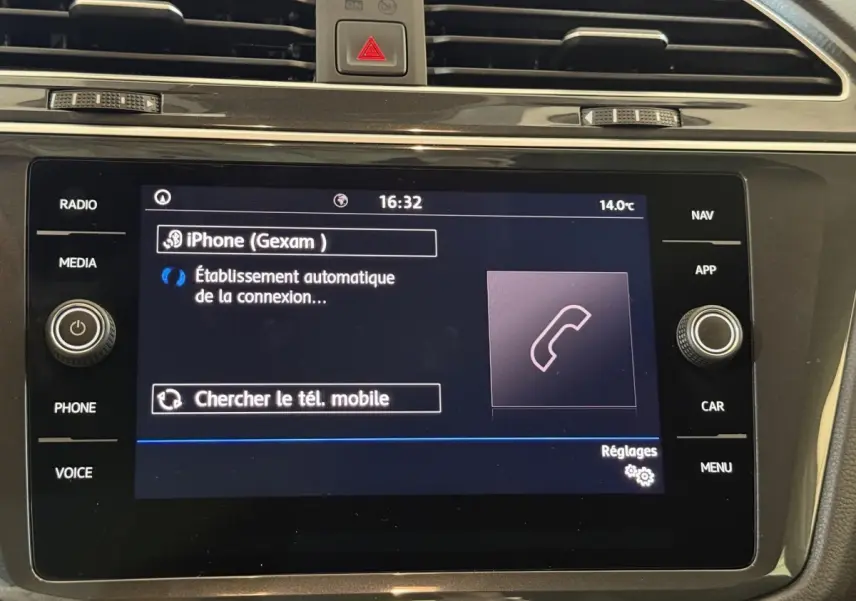 Écran tactile central du Volkswagen Tiguan 2020 affichant la connexion Bluetooth d’un iPhone, entouré de commandes noir brillant.