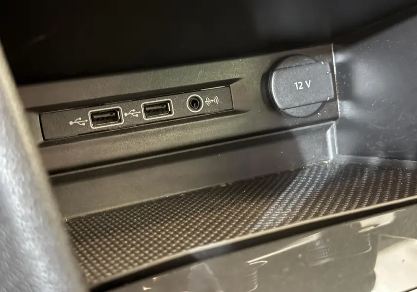 Gros plan sur les ports USB et prise 12V dans l’espace de rangement intérieur du Volkswagen Tiguan gris clair.