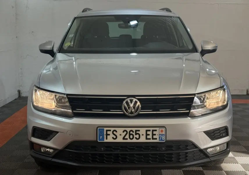 Vue frontale d'un Volkswagen Tiguan gris clair 2020 avec phares allumés et calandre noire distinctive.
