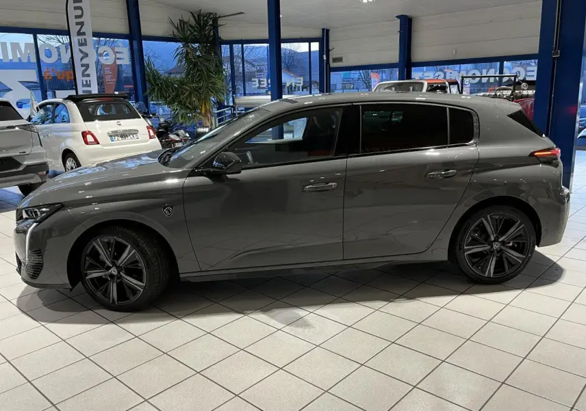 Profil côté gauche d'une Peugeot 308 gris selenium 2024 en berline GT avec jantes alliage noires en showroom.