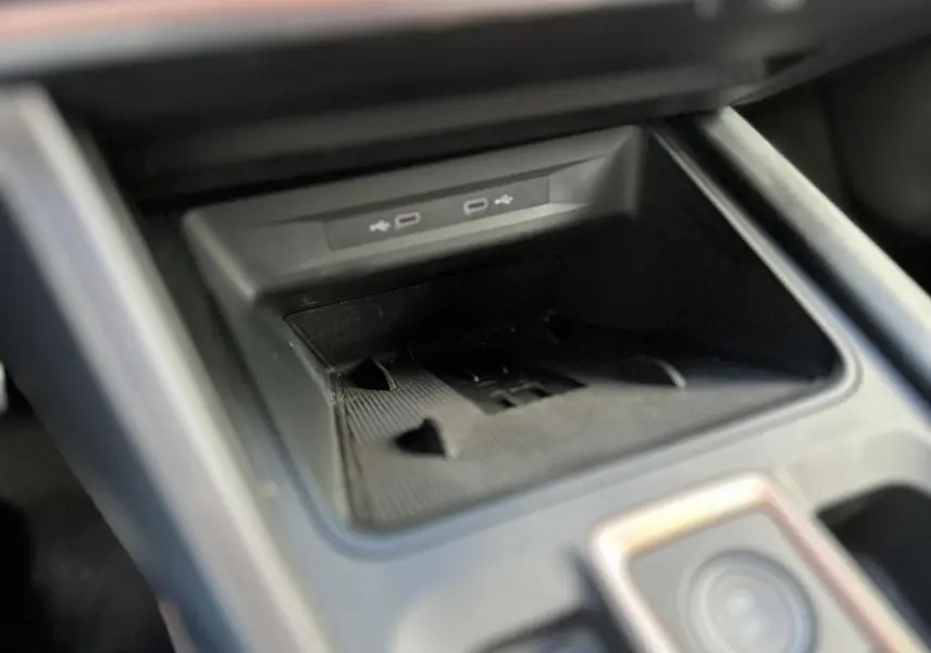 Gros plan sur la console centrale du CUPRA Formentor blanc Neige, montrant le compartiment de recharge avec ports USB.