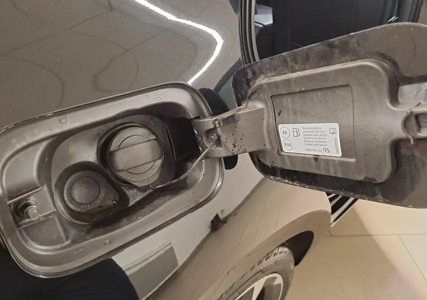 Gros plan sur la trappe de carburant ouverte côté gauche d'une CUPRA Leon 2023 noir minuit avec bouchon essence.