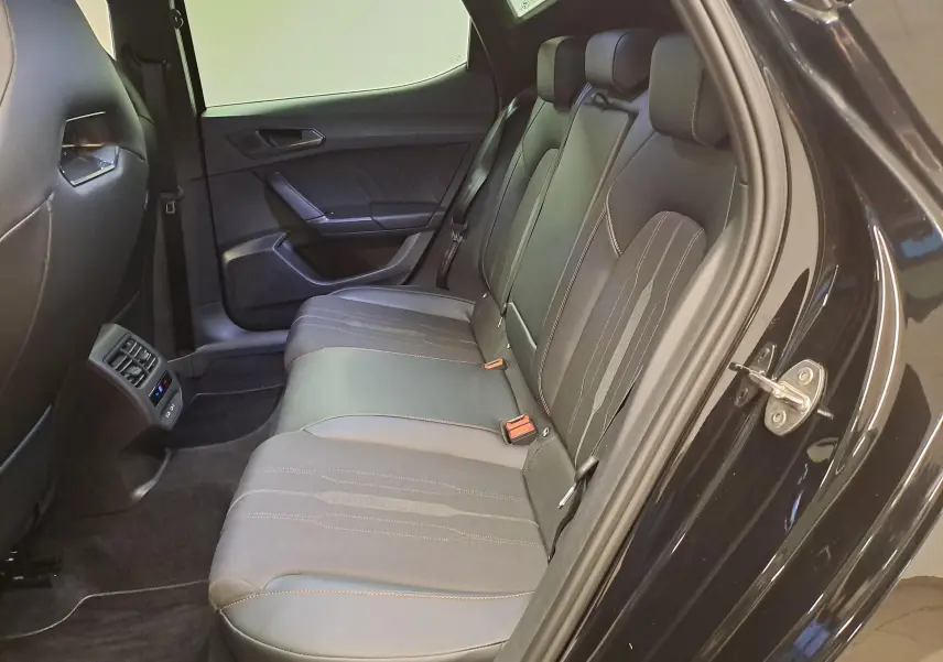 Vue intérieure côté arrière droit de la CUPRA Leon 2023 Noir Minuit, montrant les sièges arrière en cuir et tissu avec surpiqûres contrastées.