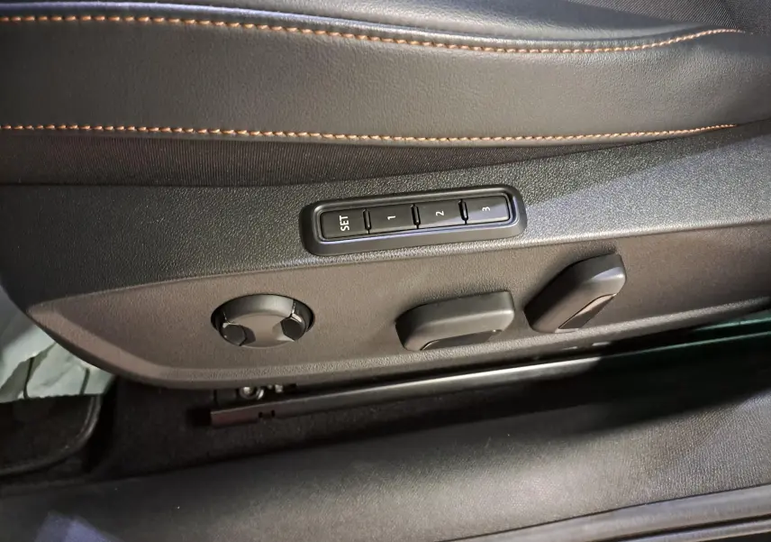 Gros plan sur les commandes de réglage électrique du siège conducteur en cuir noir avec surpiqûres orange dans une CUPRA Leon 2023.