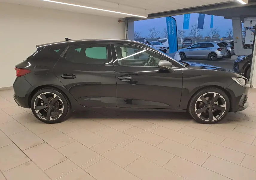Vue de profil côté droit d'une CUPRA Leon 2023 en peinture métallisée Noir Minuit, avec jantes noires distinctives.