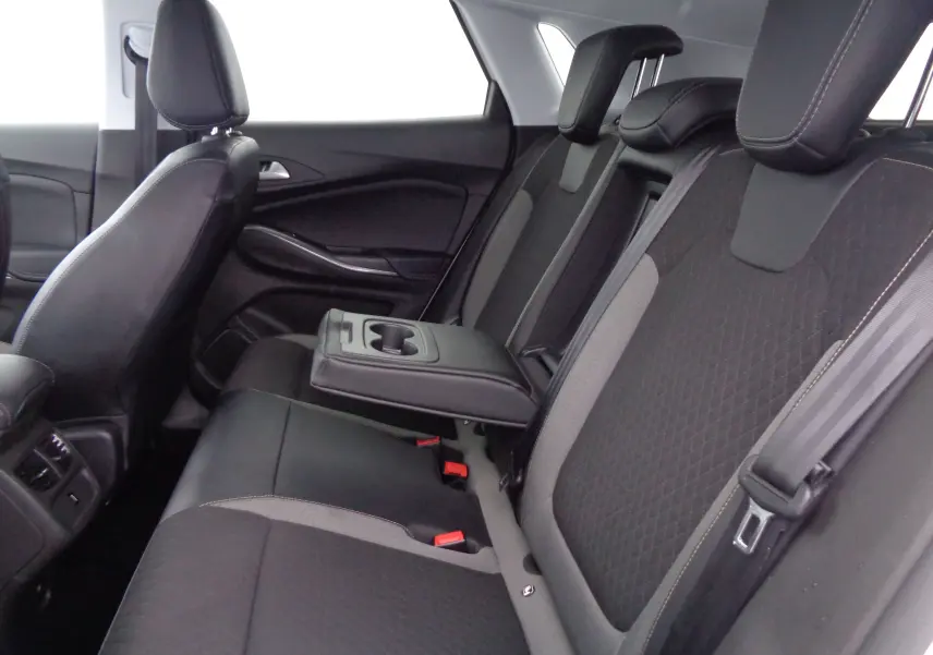 Vue intérieure arrière droite de l’Opel Grandland X 1.6 Hybrid Turbo 2021, sièges noirs avec accoudoir central relevé.